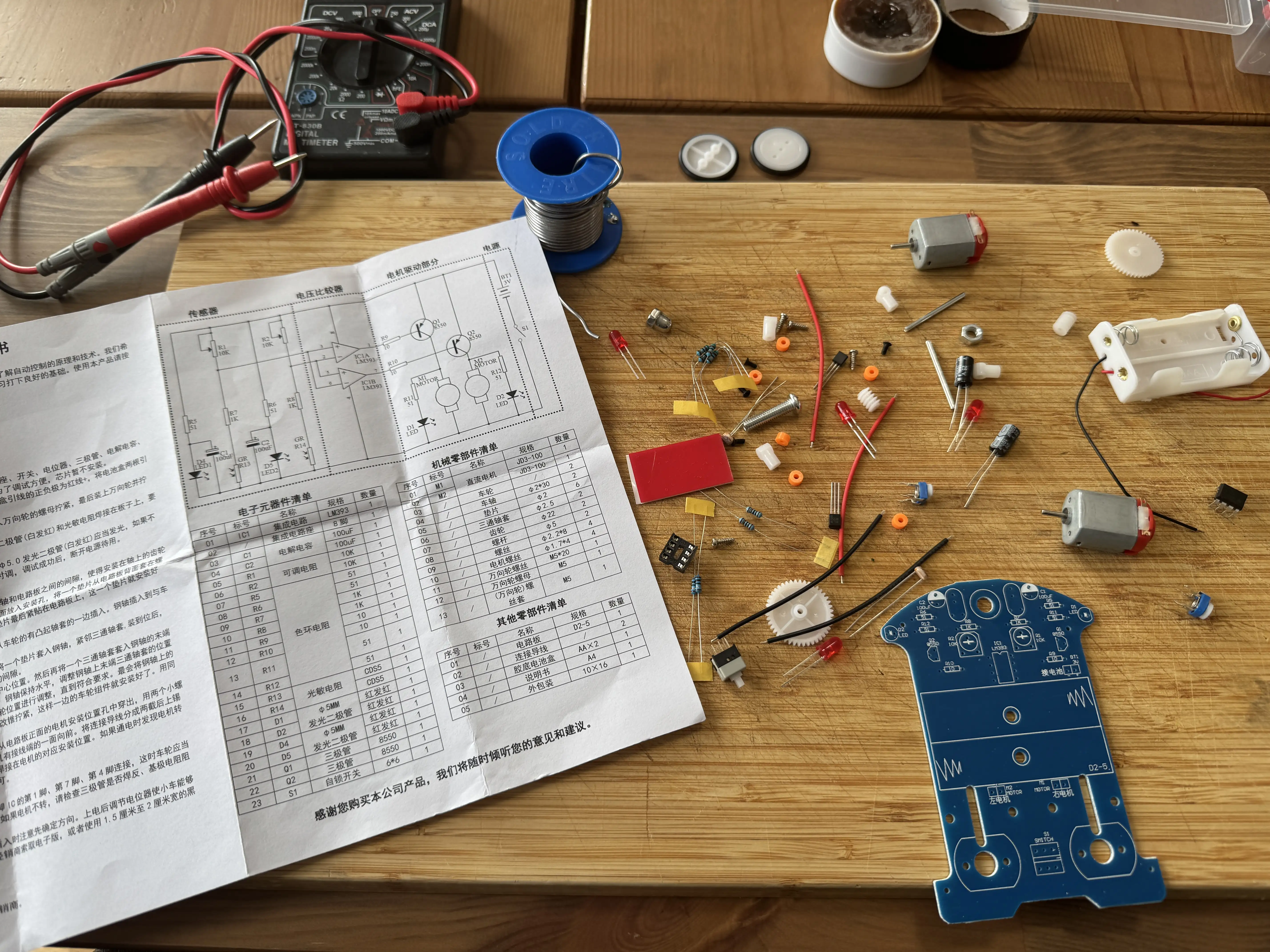 Componentele kitului desfășurate — motoare DC, suport baterie, capacitori, rezistențe colorate, schema în chineză